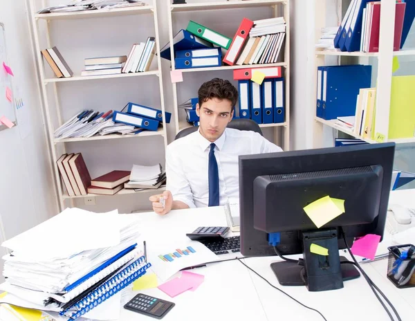 Üzletember dolgozik az irodában egy halom könyvvel és papírral. — Stock Fotó