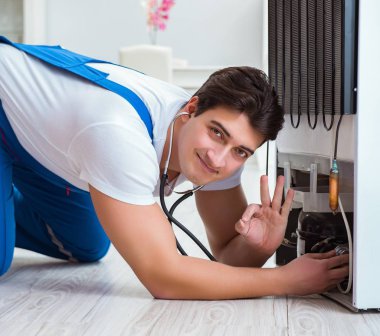 Tamirci müteahhit DIY konseptinde buzdolabını tamir ediyor.