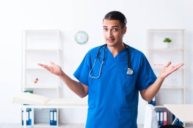 Klinikte çalışan genç erkek doktor.