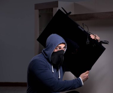 Hırsız, apartmandan televizyon çalıyor.