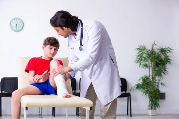 Perna ferido menino visitando jovem médico traumatologista — Fotografia de Stock