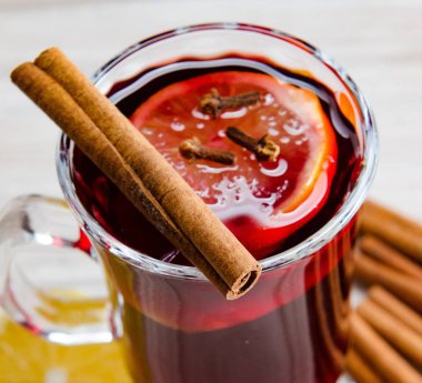 Sıcak şarap, yılbaşı masasında servis edilen bardaklarda parıldıyor.