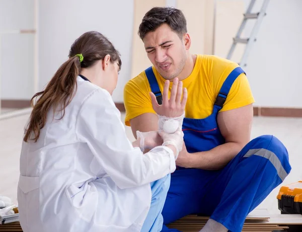 Yaralı işçiye doktor yardım ediyor. — Stok fotoğraf