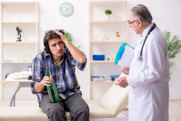 Jonge mannelijke alcoholist bezoekt oude dokter — Stockfoto