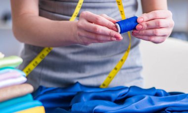 Kadın terzi dikiş dikmek için dikiş dikiyor.