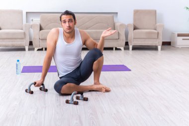 Genç adam evde antrenman ve egzersiz yapıyor.