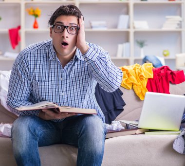 Genç adam dağınık bir odada çalışıyor.