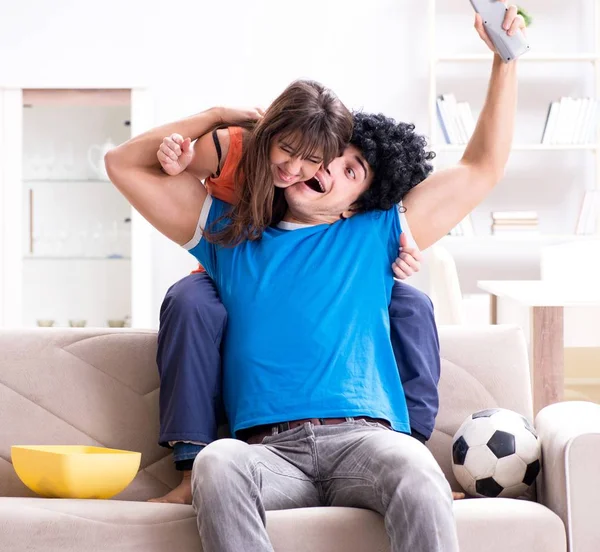 Молодой человек смотрит футбол с женой дома — стоковое фото