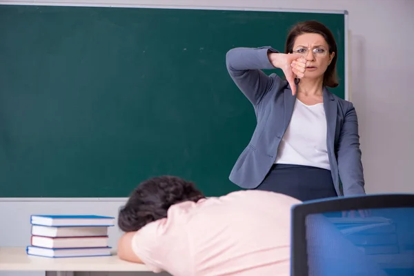 Old female teacher and male student in the classroom — Stock Photo, Image