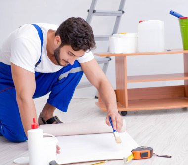 Tamirci, duvar kağıdıyla evde tadilat yapıyor.