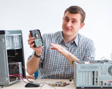 Genç teknisyen atölyede bilgisayar tamir ediyor.