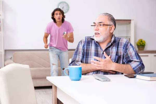 Jonge student en zijn oude opa thuis — Stockfoto