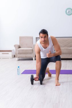 Genç adam evde antrenman ve egzersiz yapıyor.