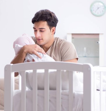 Genç baba evde yeni doğmuş bebekle eğleniyor.