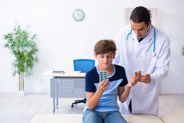 Joven médico examinando a un niño en la clínica —  Fotos de Stock