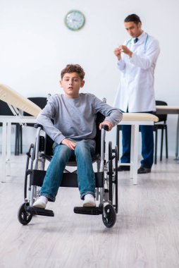 Genç erkek doktor pediatrist ve tekerlekli sandalyedeki çocuk.