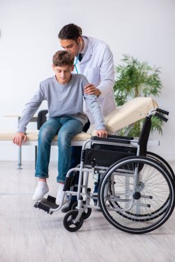 Genç erkek doktor pediatrist ve tekerlekli sandalyedeki çocuk.