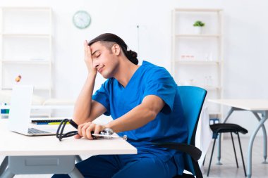 Klinikte çalışan genç erkek doktor.