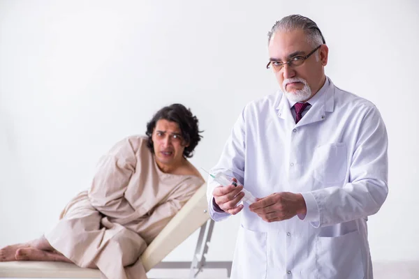 Genç hastayı muayene eden yaşlı erkek doktor psikiyatristi — Stok fotoğraf