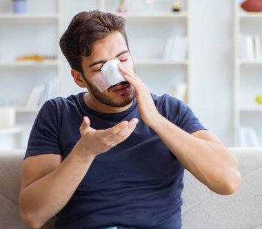 Genç adam estetik cerrahi burnundan sonra evde iyileşiyor.