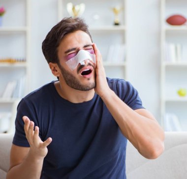 Genç adam estetik cerrahi burnundan sonra evde iyileşiyor.