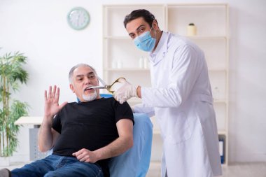 Yaşlı adam estetik ameliyat için genç doktoru ziyaret ediyor.