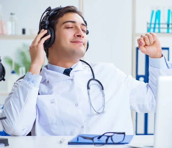 Glad upphetsad läkare lyssnar på musik under lunchen paus i ho — Stockfoto