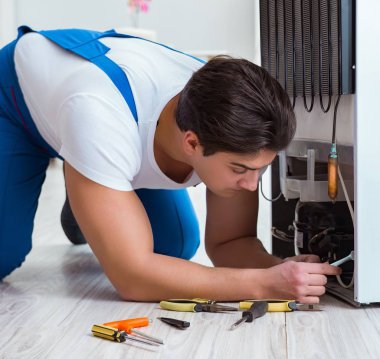 Tamirci müteahhit DIY konseptinde buzdolabını tamir ediyor.