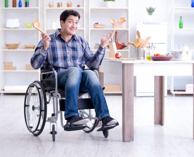 Engelli genç koca mutfakta çalışıyor.