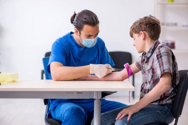 Genç çocuk hastanede doktoru ziyaret ediyor.