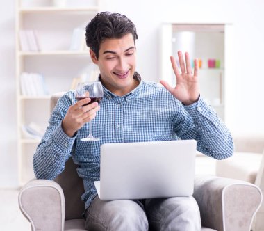 Genç adam evde şarap içiyor.