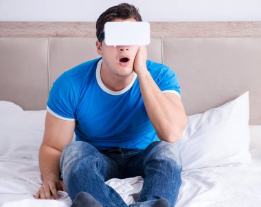 Yatakta sanal gerçeklik başlığı takan genç bir adam.