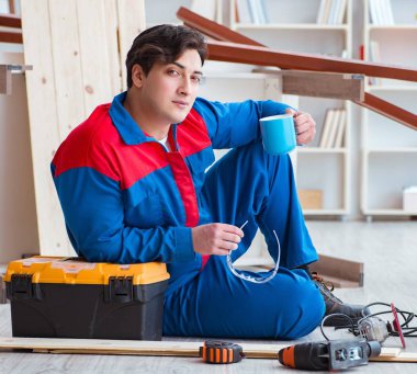 Genç marangoz ahşap kalaslarla çalışmaya ara veriyor.