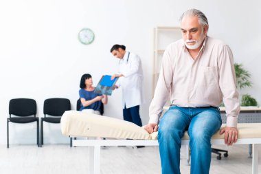 Yaşlı çift genç erkek doktoru ziyaret ediyor.