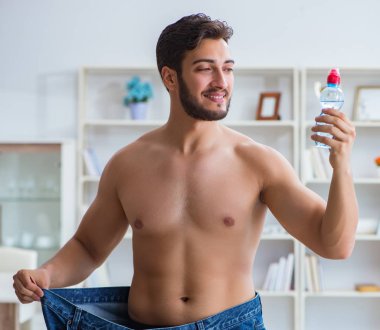 Kilo verme konseptinde büyük beden pantolon giyen bir adam.