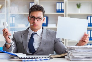 Ofiste sigara içen bir iş adamı elinde boş bir mesaj tutuyor.