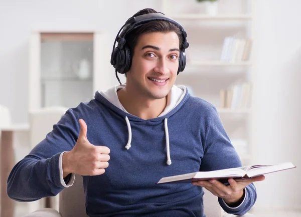 Joven leyendo libro y escuchando audio libro —  Fotos de Stock