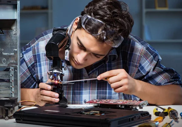 Reparatören försöker reparera laptop med miscroscope — Stockfoto