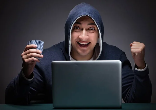 Jovem usando um capuz sentado na frente de um computador portátil — Fotografia de Stock