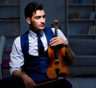 Genç müzisyen evde keman çalıyor.