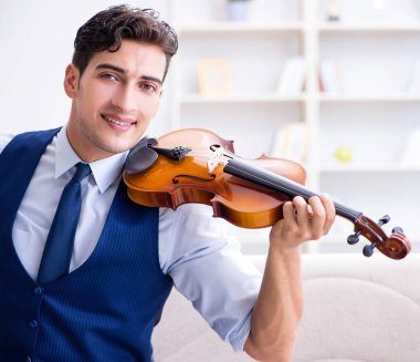 Genç müzisyen evde keman çalıyor.