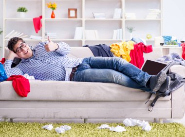 Genç adam dağınık bir odada çalışıyor.