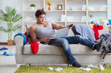 Genç adam dağınık bir odada çalışıyor.