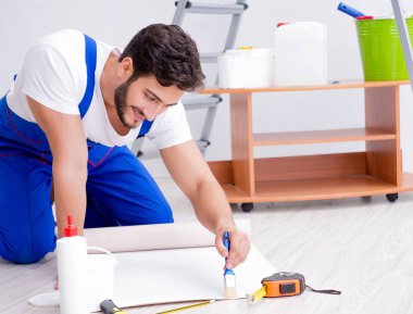 Tamirci, duvar kağıdıyla evde tadilat yapıyor.