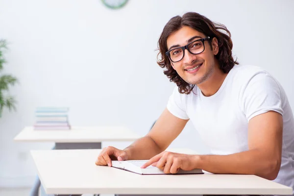 Jonge mannelijke student zit in de klas — Stockfoto