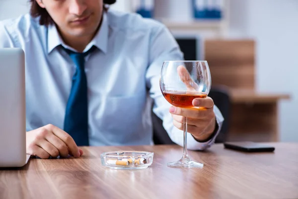 Male employee drinking alcohol and smoking cigarettes at workpla — Stock Photo, Image