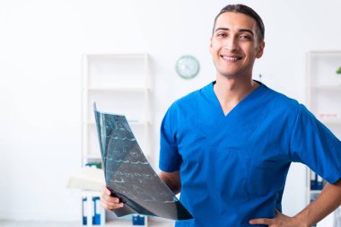 Klinikte çalışan genç erkek doktor.