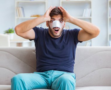 Genç adam estetik cerrahi burnundan sonra evde iyileşiyor.