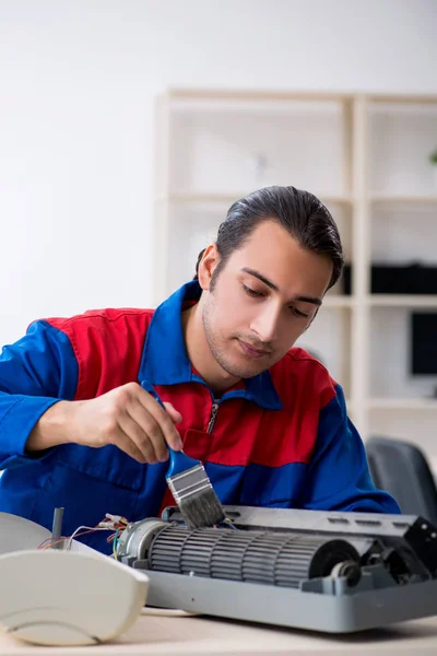 Jovem reparador reparando ar-condicionado no centro de garantia — Fotografia de Stock