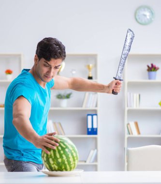 Evde karpuz yiyen bir adam.